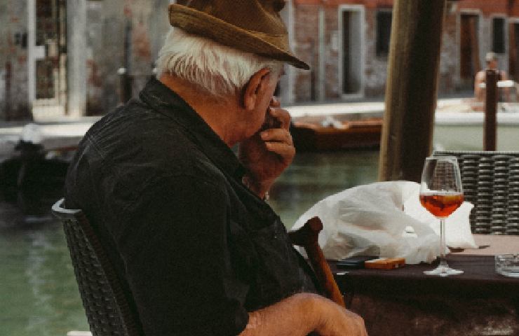 Uomo che beve un bicchiere di vino davanti a un canale veneziano