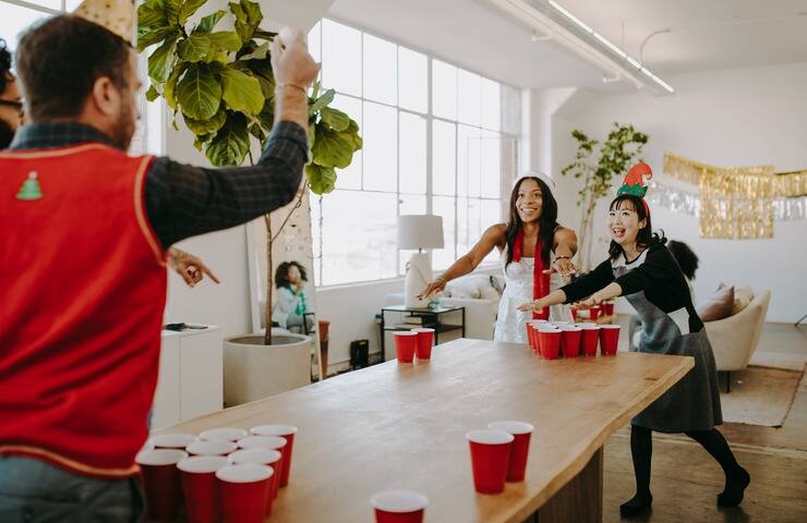 Amici vestiti a tema natalizio che giocano a Beer pong