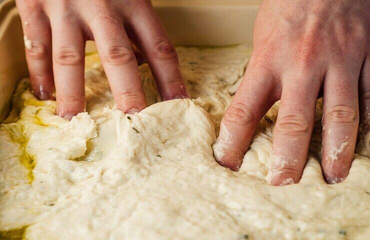 mani che impastano la focaccia ligure